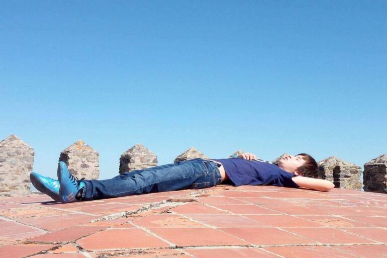 man lying on a stone wall looking at the sky - Stoic in Training: It’s About Acceptance, Not Indifference