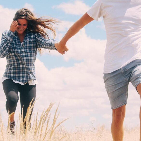 Couple holding hands, happily walking through grass - How to Live With Zen-Inspired Naturalness in the Modern World