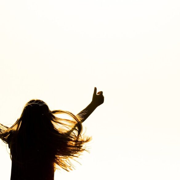 Girl with arms stretched in air in joy - Why Accepting Our Truth Can Lead Us To a Life of Peace