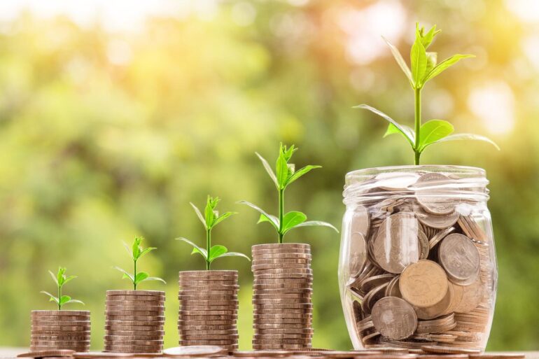 Plants growing out of stacks of coins and a jar of coins - Pure Abundance: Create It by Identifying Your True Values