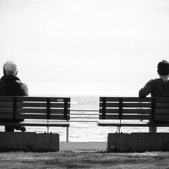 Black and white photo of two men sitting on benches - The Value of Pausing and Reflecting in the Present Moment