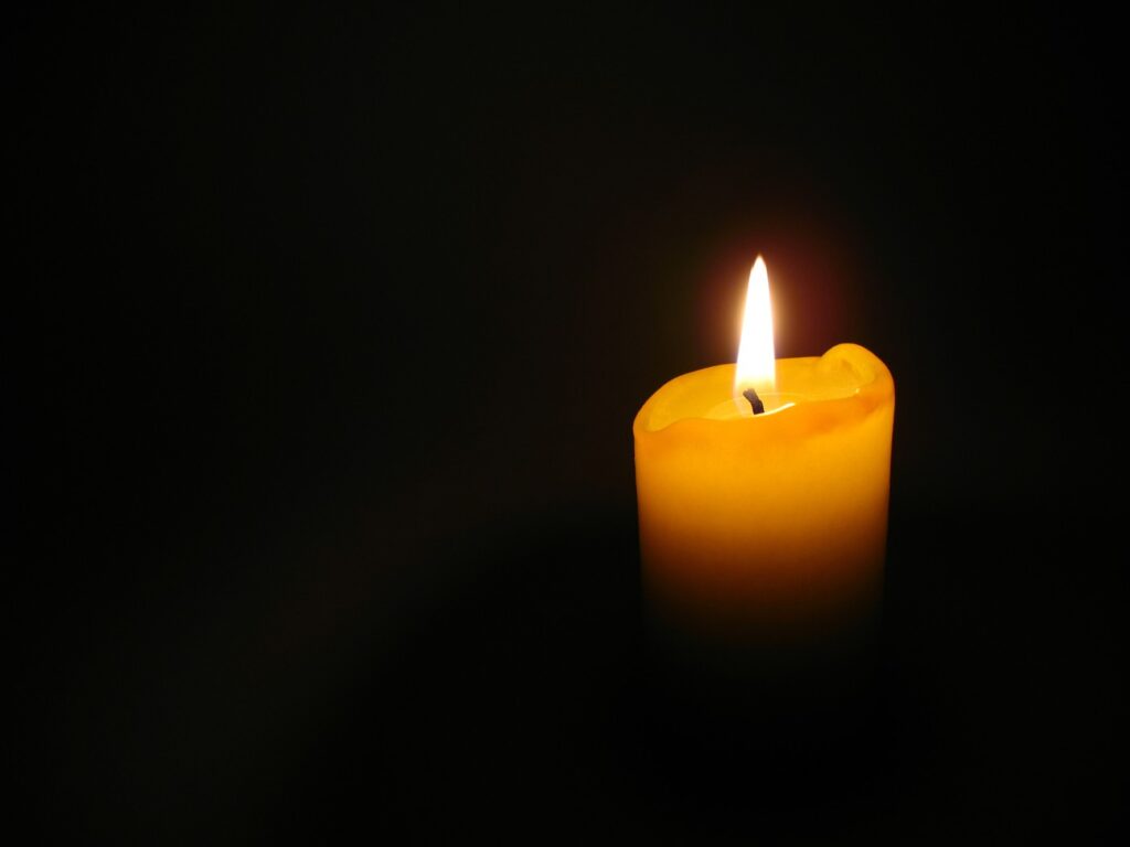 Lit yellow candle against dark background - Practice Shamata by Observing a Candle for 3 Minutes a Day