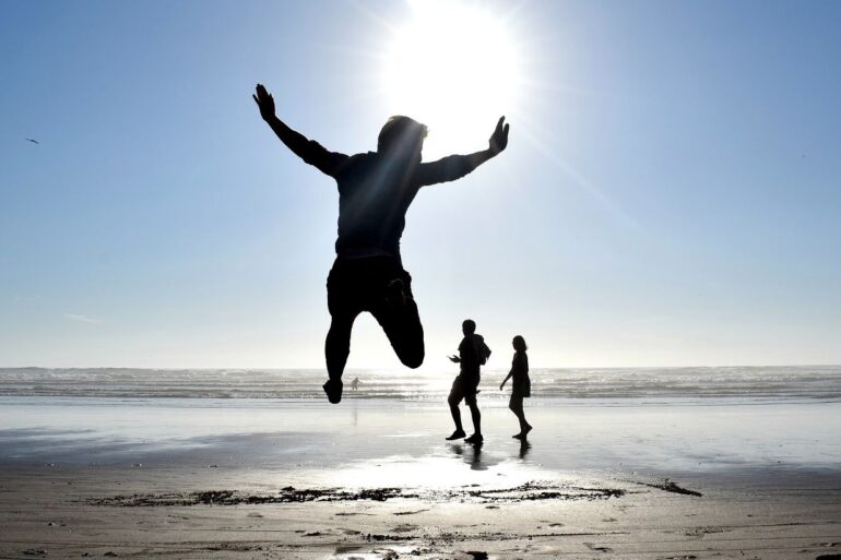 MINDFUL REFLECTIONS: Pain and ignorance give birth to darkness and more 21 Three silhouettes on sunlit beach, including one of boy jumping - Mindfully Letting the Light of the Sun Drown Out Darkness