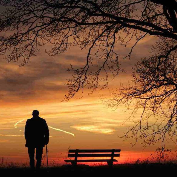 Silhouette of a man standing alone next to a park bench watching the sunset - 3 Ways Avoiding Unwanted Sound Can Improve Your Health