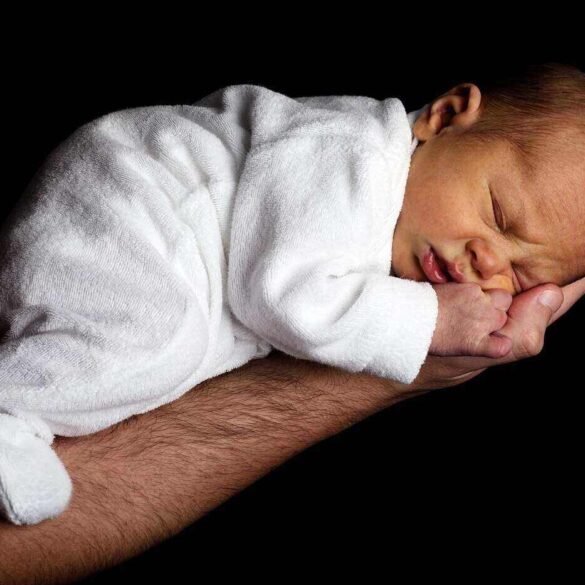 man's extended arm holding a newborn baby