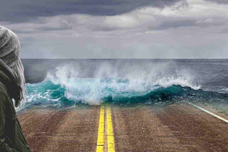art - woman watching the sea take over a road