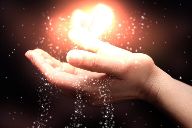Person catching illuminated heart in hand
