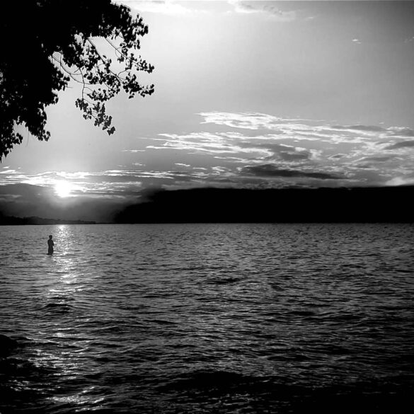 Black-and-white photo of someone standing in river - "Seneca Nation" and 5 More Poems About Life’s Beauty
