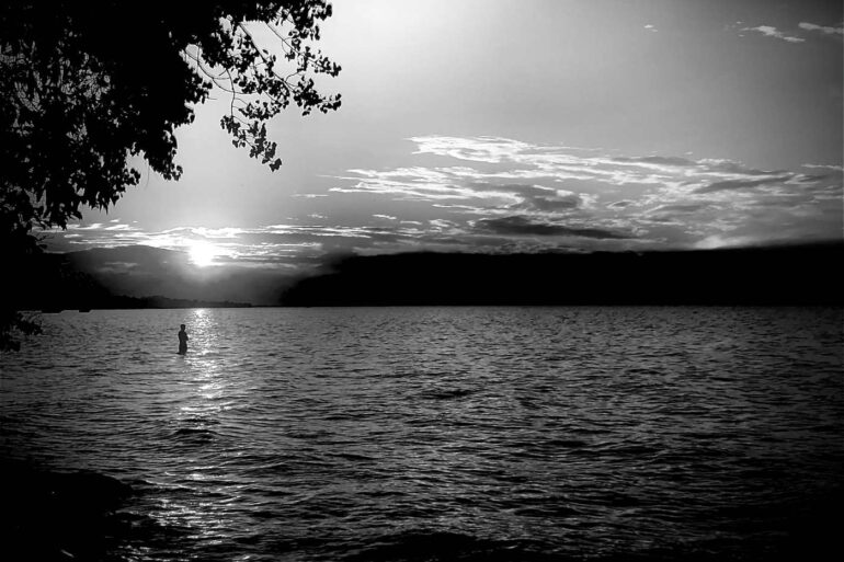 Black-and-white photo of someone standing in river - "Seneca Nation" and 5 More Poems About Life’s Beauty