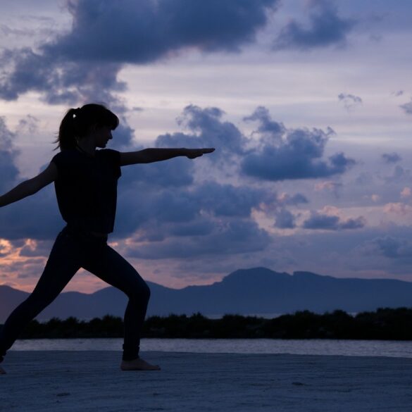 Shadowy picture of woman doing Yoga on beach