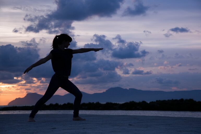 Shadowy picture of woman doing Yoga on beach