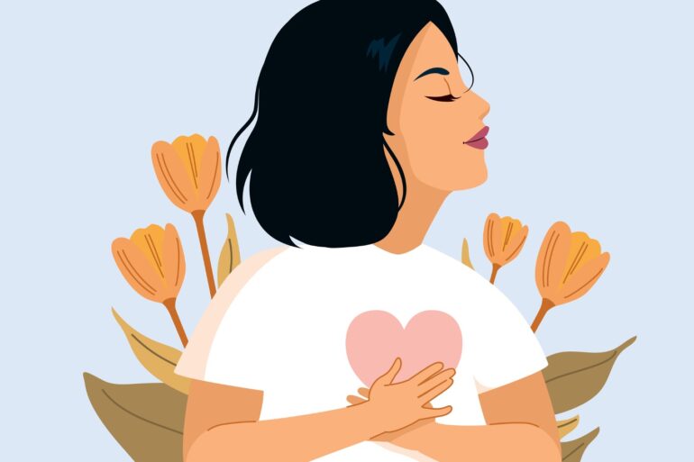 Woman holding heart in front of self, expressing self-love