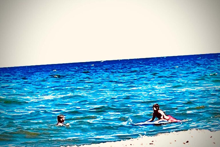 Two kids swimming at a beach - 7 New Poems About Humanity, Including "Support Group"