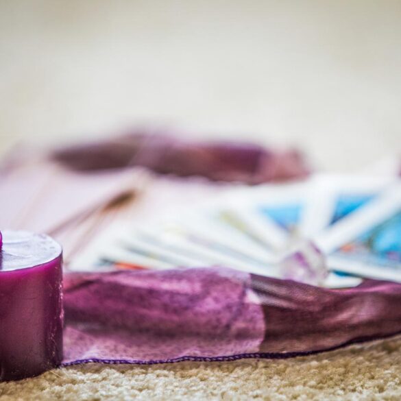 Tarot cards on purple scarf, next to purple candle - 10 Steps to Meditation and Journaling With Your Tarot Deck