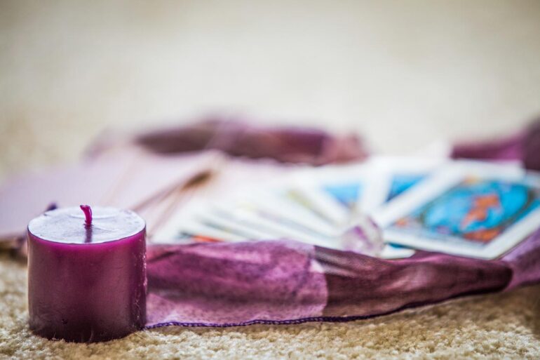 Tarot cards on purple scarf, next to purple candle - 10 Steps to Meditation and Journaling With Your Tarot Deck
