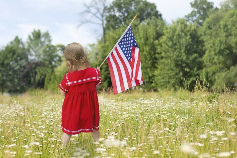 Little girl holding American flag in a field - A Father’s Perspective on Trump: We Must Not Be Silent