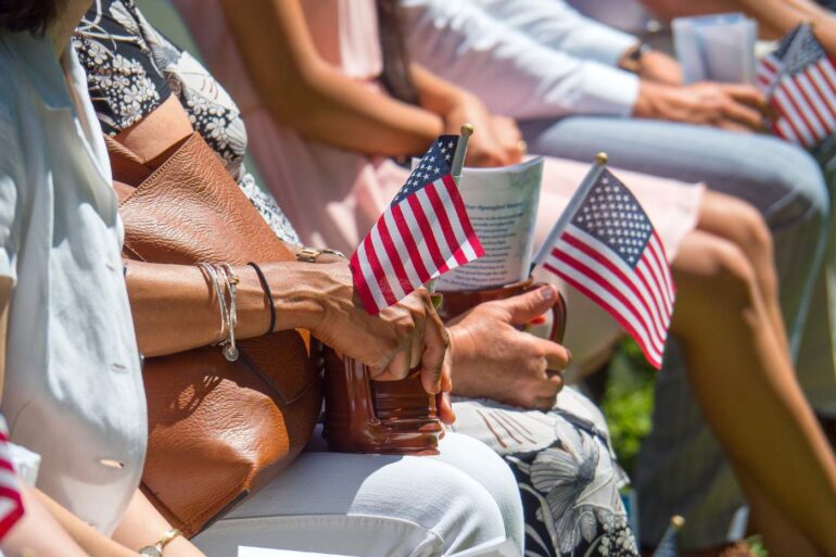 Various people sitting in chairs, holding small American flags - Our Natural Identity: Can It Overpower Political Discord?