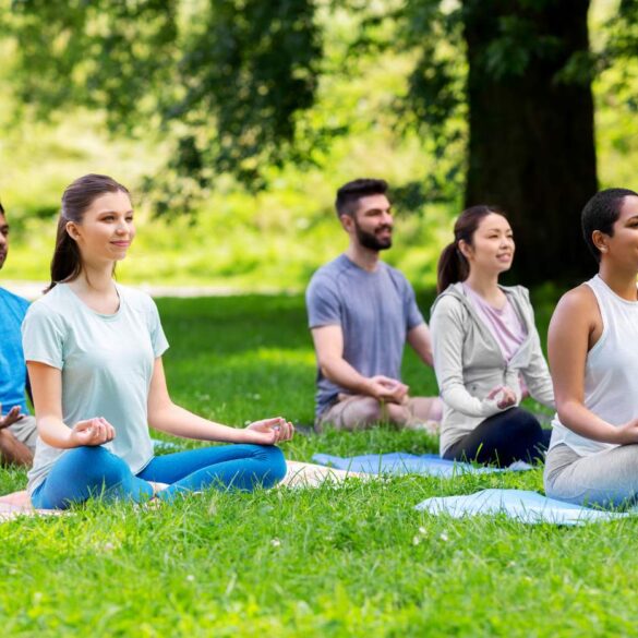Five people meditating on grass outdoors
