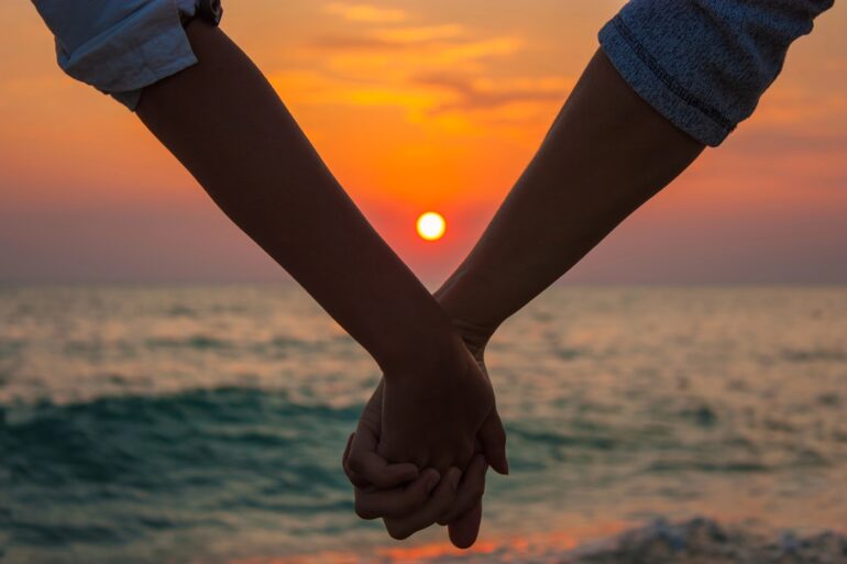 Couple holding hands at sunset