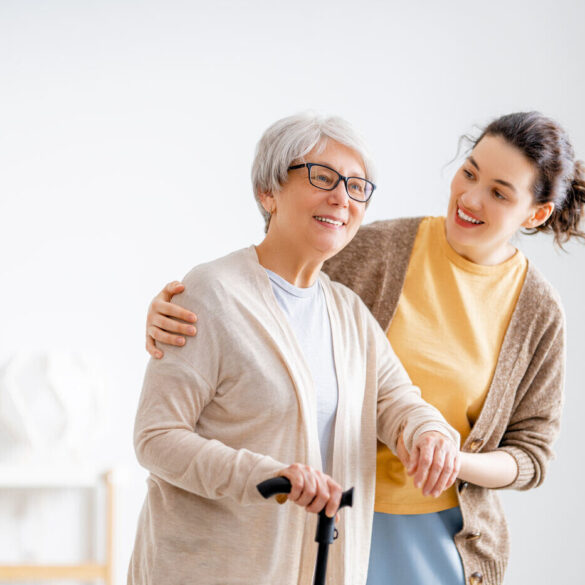 Younger woman caring for senior woman with cane - Collective Mindfulness for Caregivers: 6 Uplifting Benefits