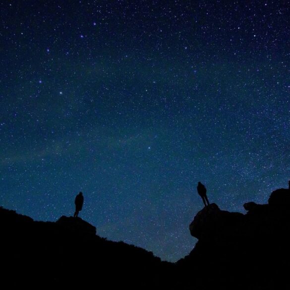 Two silhouettes looking up at night sky from rocky terrain - Dump Your Baggage and Connect With Mind, Spirit and Universe