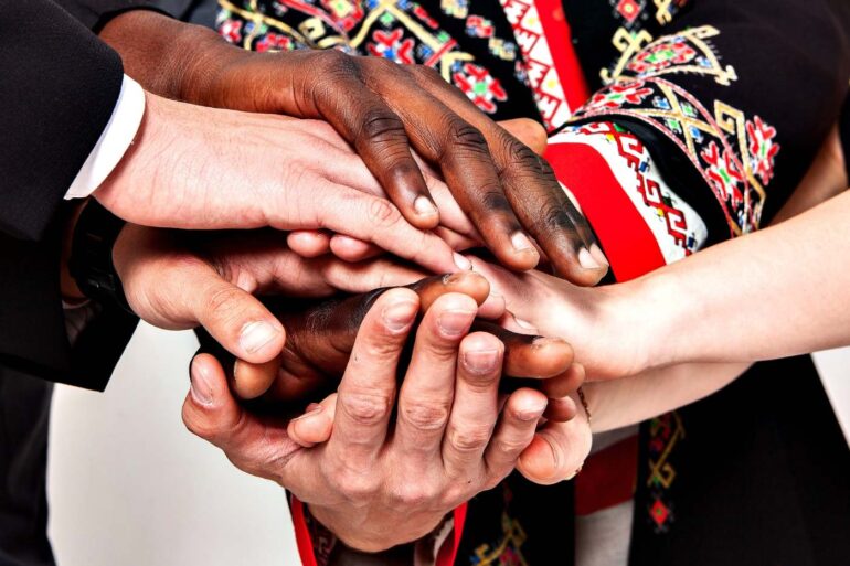 Diverse group of hands on top of each other in solidarity - How Inner Peace Leads to Outer Peace and Stable Communities