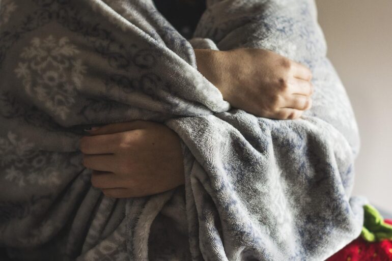 Person wrapped in warm grey blanket - How I Embraced Softness as a Life-Changing Remedy for Fear