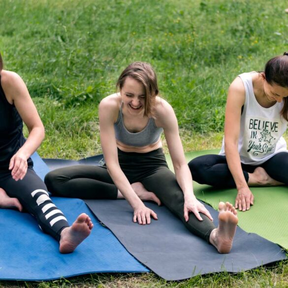 Three young women doing Yoga in the grass together
