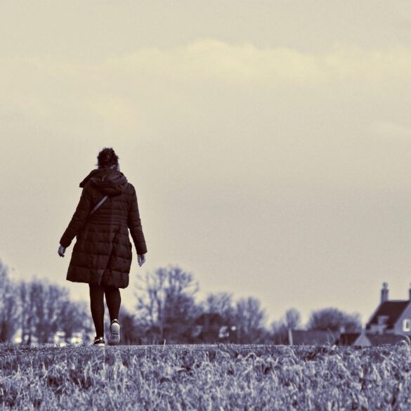Woman walking in field next to house - 5 Signs of Quiet Burnout and What You Can Do About It
