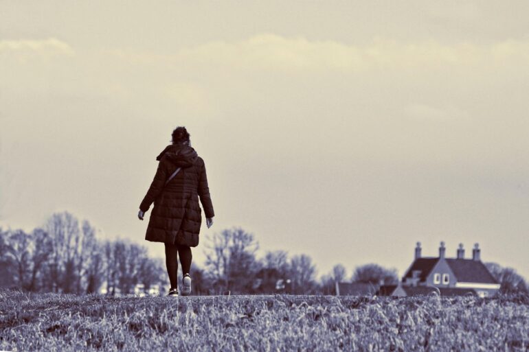 Woman walking in field next to house - 5 Signs of Quiet Burnout and What You Can Do About It