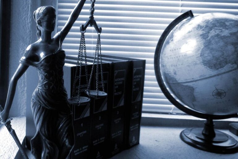 Lady Justice statue next to legal books and globe - The Gift of Privilege: What Does This Really Mean?