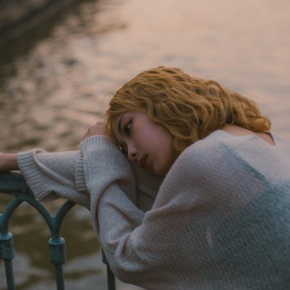 Sad woman with head laying on side of bridge - An Induced Disease: How to Perceive Panic and Stress