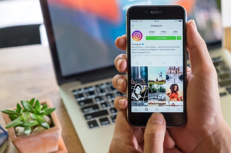 Instagram app open on a person's phone, next to a laptop - 10 Ways Leaving Social Media Helps You Life Your Best Life