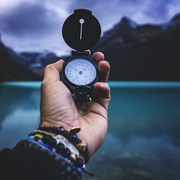 Man holding compass in hand next to mountains and lake - The Body’s Subtle Language: Why Is It Such a Big Deal?