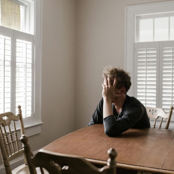 Confused man leaning on wooden table - Gaslighting: What It Is and 3 Effective Ways to Push Back