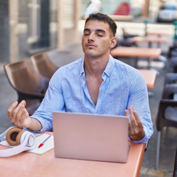 Man meditating at computer outside coffee shop - Buddhist Principles: 5 Valuable Ways to Add Them to Your Day