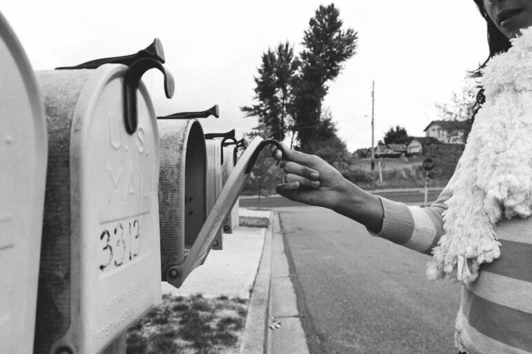 Woman opening mailbox on suburban street - The Language of Grief: Creating a New Life After Loss