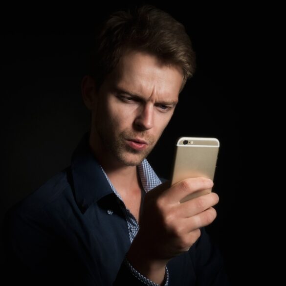 Young man staring at smartphone - Our Personhood: Will Humanity Let AI Annihilate It?