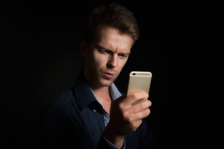 Young man staring at smartphone - Our Personhood: Will Humanity Let AI Annihilate It?