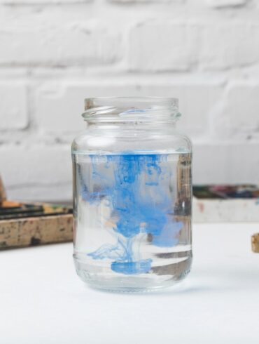 Glass jar full of blue paint next to paintbrushes on table - Take Stock of Your Precious Life: An Inspiring Fiction Story