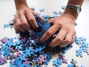 Person wearing watch, grabbing puzzle pieces - How to Reduce Your Brain’s Blind Spots With Simple Training