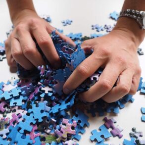 Person wearing watch, grabbing puzzle pieces - How to Reduce Your Brain’s Blind Spots With Simple Training