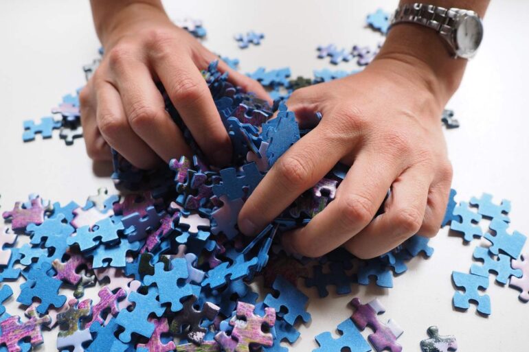 Person wearing watch, grabbing puzzle pieces - How to Reduce Your Brain’s Blind Spots With Simple Training