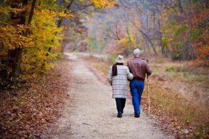 Senior couple walking down trail in fall - Exercise as Play: A Small Shift Makes a Big Difference