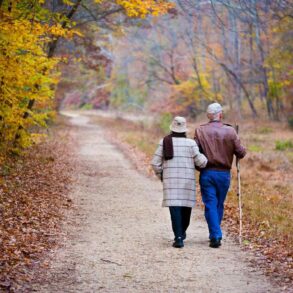 Senior couple walking down trail in fall - Exercise as Play: A Small Shift Makes a Big Difference