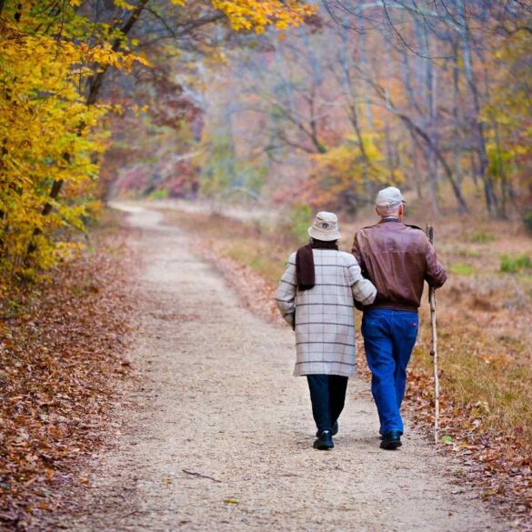 Senior couple walking down trail in fall - Exercise as Play: A Small Shift Makes a Big Difference