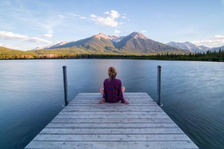 Woman sitting on dock by water, relaxing - Hello 2026: Time to Slow Down and Reflect