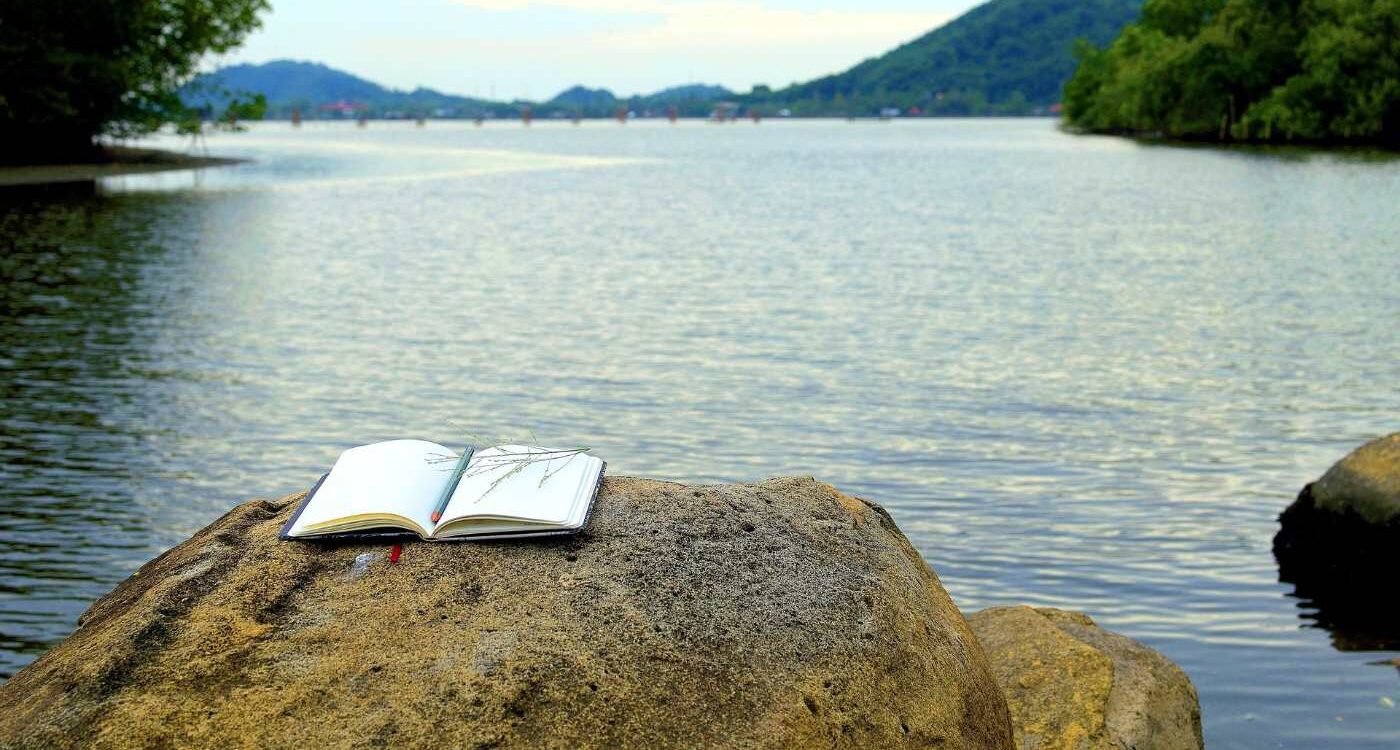 Writing notebook on rock next to river - From Confusion to Clarity: 3 More Stages on a Spiritual Path