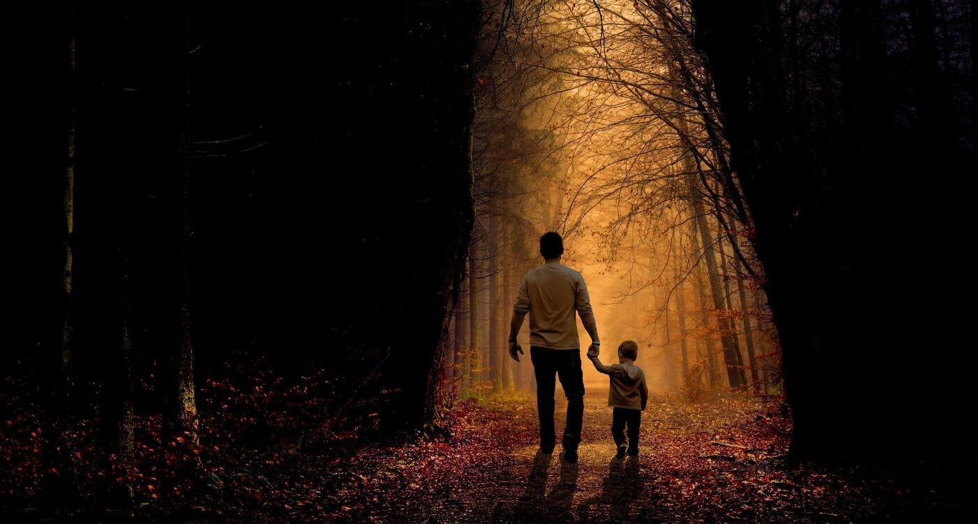 Father and son walking on sunlit path through dark woods - 5 Fun and Playful Ways to Help Children Explore Mindfulness
