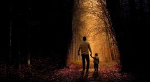 Father and son walking on sunlit path through dark woods - 5 Fun and Playful Ways to Help Children Explore Mindfulness